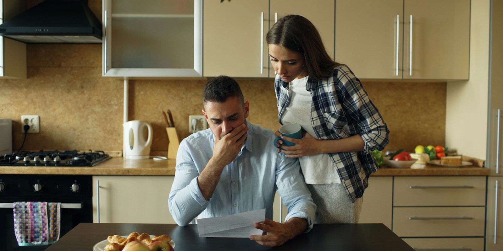 Casal na cozinha de casa analisando contas e despesas da família