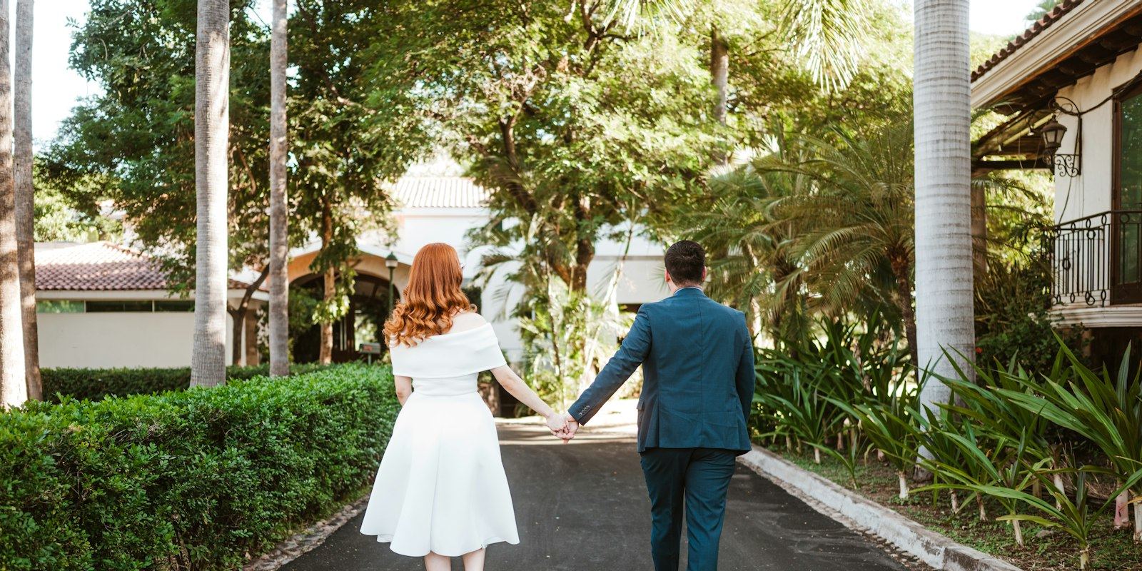 Casal caminhando de mãos dadas em uma rua arborizada